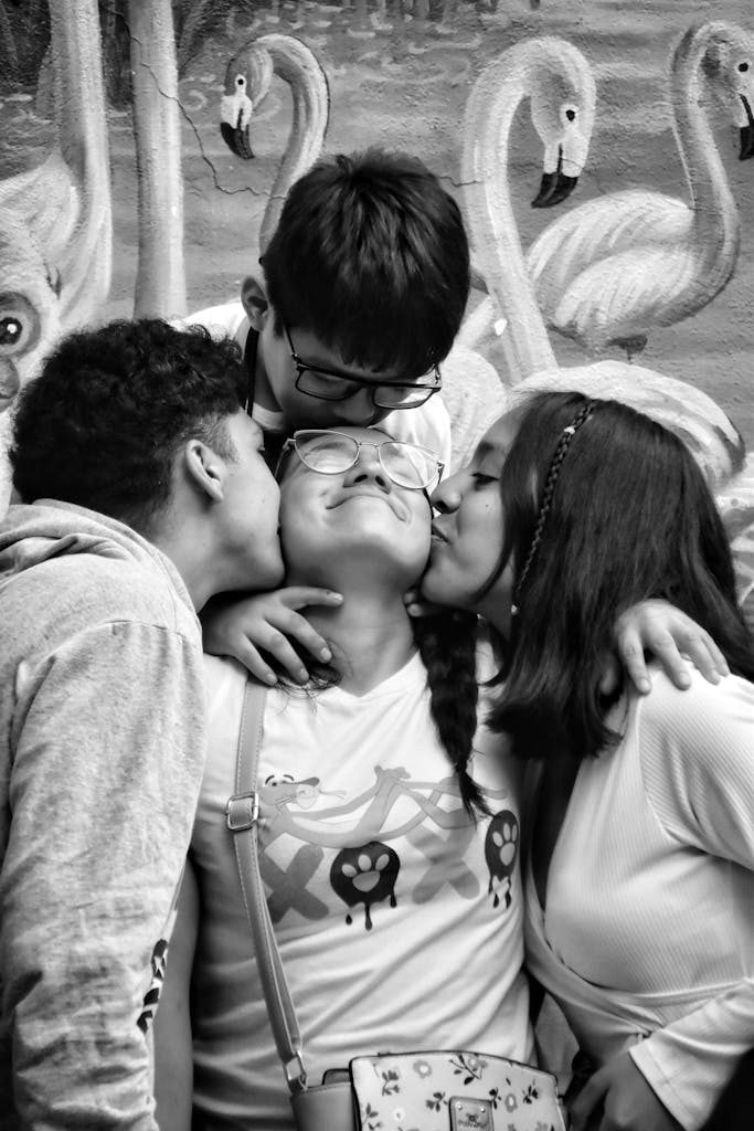 A black and white photo of three people kissing