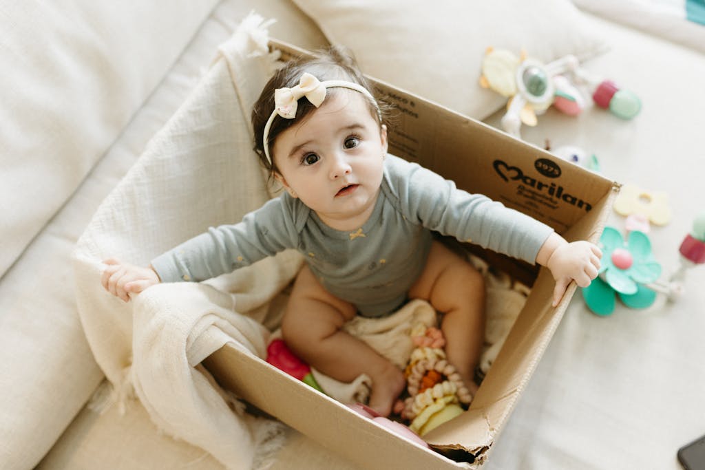 A baby in a cardboard box with a toy